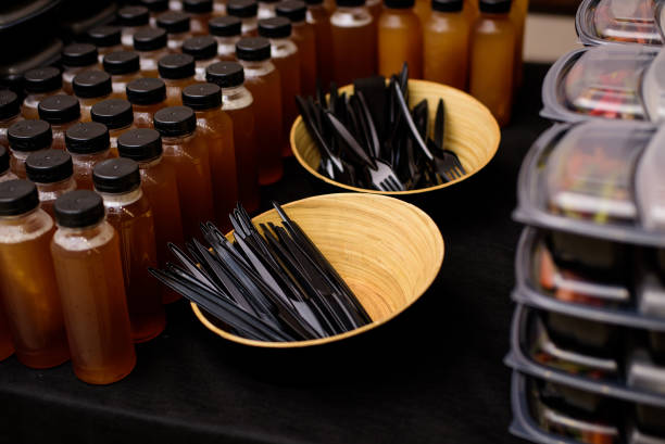 Black plastic knives and forks in plates. Catering